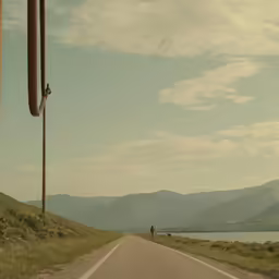 a man is standing on a road with mountains in the background