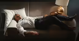 man in white shirt laying on a white couch