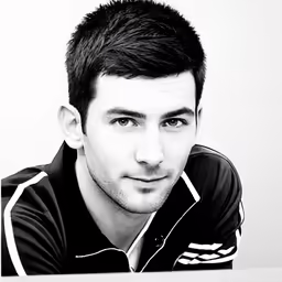 a man with dark hair, wearing a black polo shirt