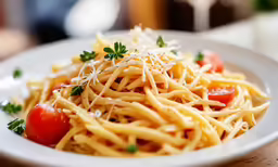 spaghetti and cherry tomatoes with parmesan cheese is served on a white plate