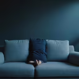 the woman is lying on the couch under the large pillow