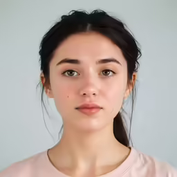 a young woman with a ponytail and bangs wearing a pink shirt
