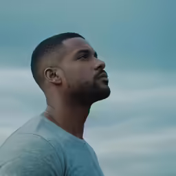 a man looking away with the sky in the background