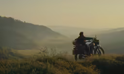 two people stand on top of the hills holding their bikes