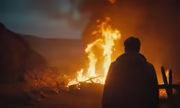 a person standing in front of a burning bonfire