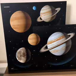 two space paintings of the planets mounted to a wall