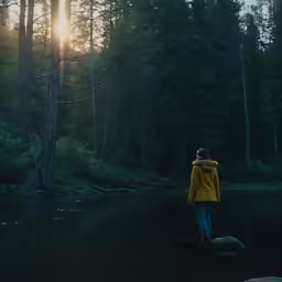 a person wearing a yellow jacket standing on a river bank