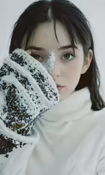 a young woman in a winter coat covers her eyes from the cold with powder