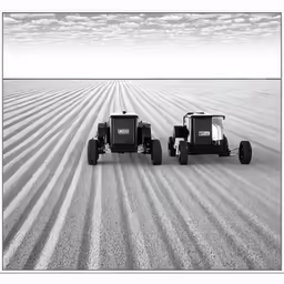 two three wheeled vehicles on an arid field