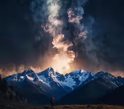 a person stands on a hill near mountains at night