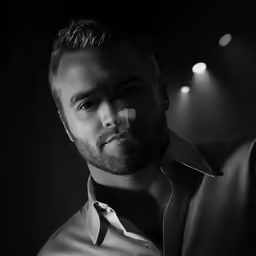 a man in a tie looking down with lights on the ceiling