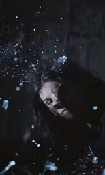 a woman in a black top is standing under the rain