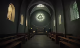a dark and empty church with pews, windows and a large window