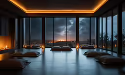 a room with many pillows on the floor and lights over the windows