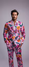 the man is wearing colorful suit with flowers,a man in pink floral suit with white shirt