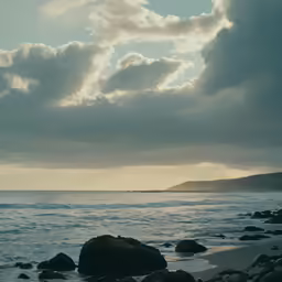 a cloudy day along the beach with rocks