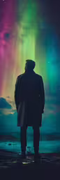 a man watching the aurora bores from the ocean,a man is standing in the snow staring at an aurora