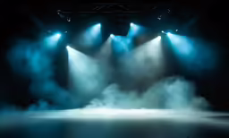bright blue lights illuminate dark stage with fog