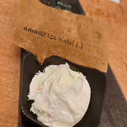 whipped cream in a black bowl is next to a receipt