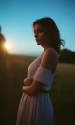 a woman in a white dress standing in the sunlight