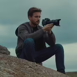 a man with a camera on a rock