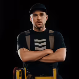 a man is wearing a black and brown shirt and he has his arms folded