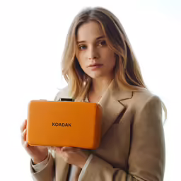 a woman is holding a orange object for advertising