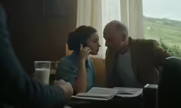 a woman is sitting next to a man while talking on the phone