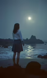 a woman standing on a beach under the moonlight