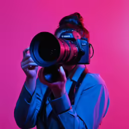 the young woman is using the large camera for a picture