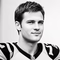a black and white photo of a man with short hair wearing football uniforms