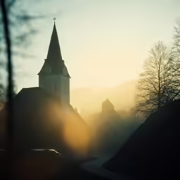 a church spire is seen with the sun peeking through