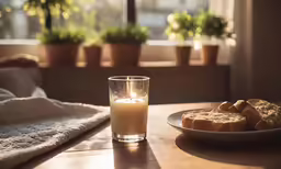 a lit candle and cookie in front of a window with a blanket