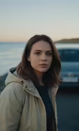 a young lady standing next to the ocean