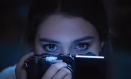 woman looking through camera lens in dark light