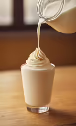a shot glass with a cream cream filled with liquid being poured
