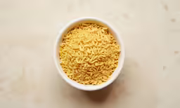 a white bowl filled with noodles next to a wall