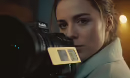 a girl holding a digital camera and looking at it