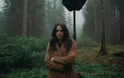 a young woman standing in a forest posing for a photo