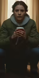 the girl is holding a cup in her hands