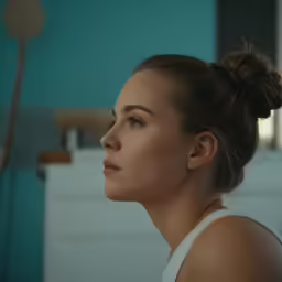 a woman in a top knot with long hair is looking into the distance