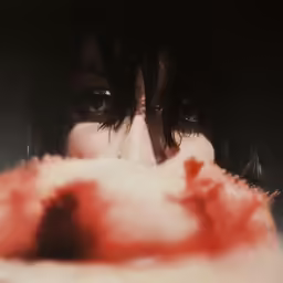 a woman looking into the camera with red smoke covering her face