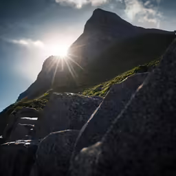 the sun is shining behind rocks near a mountain