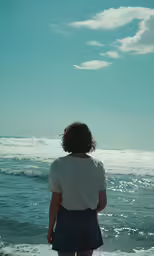 a young girl looking out at the ocean from the beach
