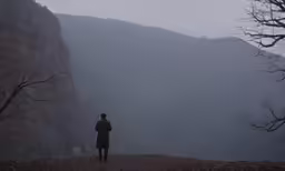 the man is standing alone by the river