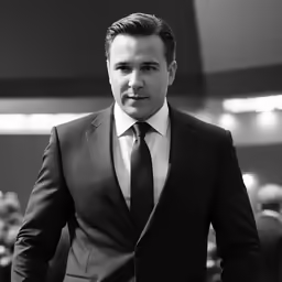 a young man wearing a suit and tie posing for the camera