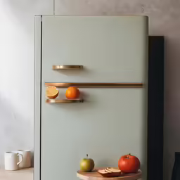 three plates and two slices of fruit are attached to the side of the fridge