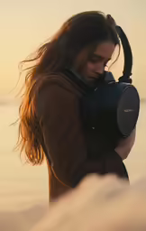 a woman standing on top of a beach while holding a camera