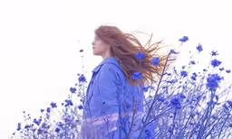 a woman with long red hair standing in blue flowers