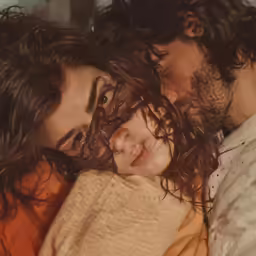 a woman laying on a man and the man has his eyes closed